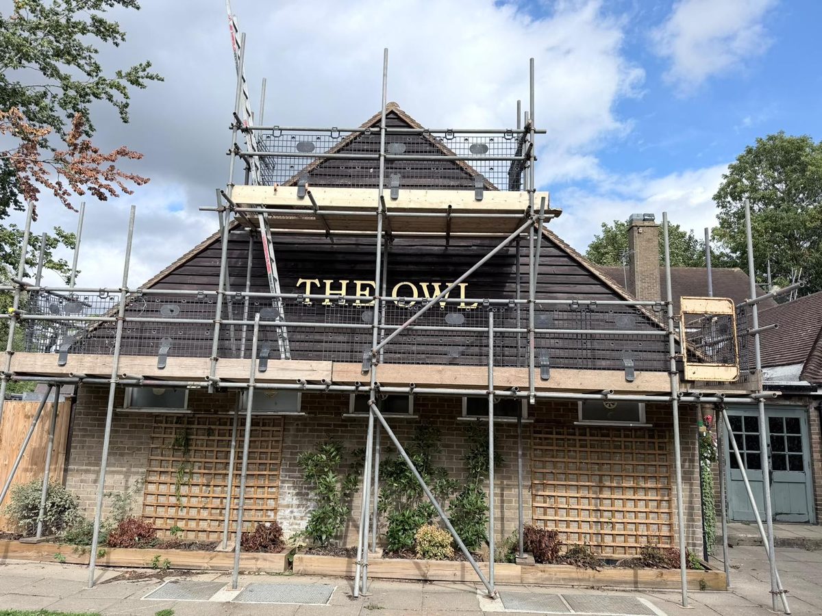 BSL scaffold with a boarded lift and gable access across the front of The Owl pub, its gold lettering visible through the mesh guards