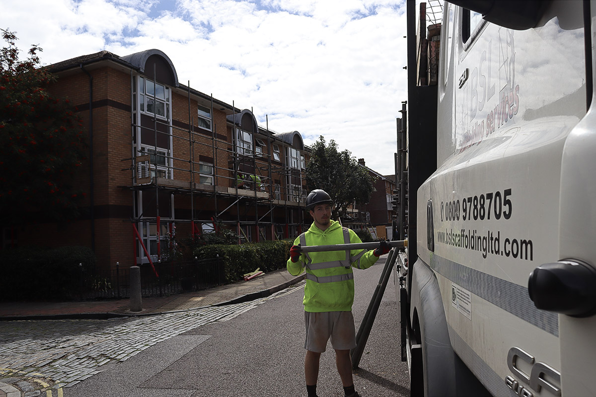 BSL liveried lorry on site with a scaffolder carrying tube